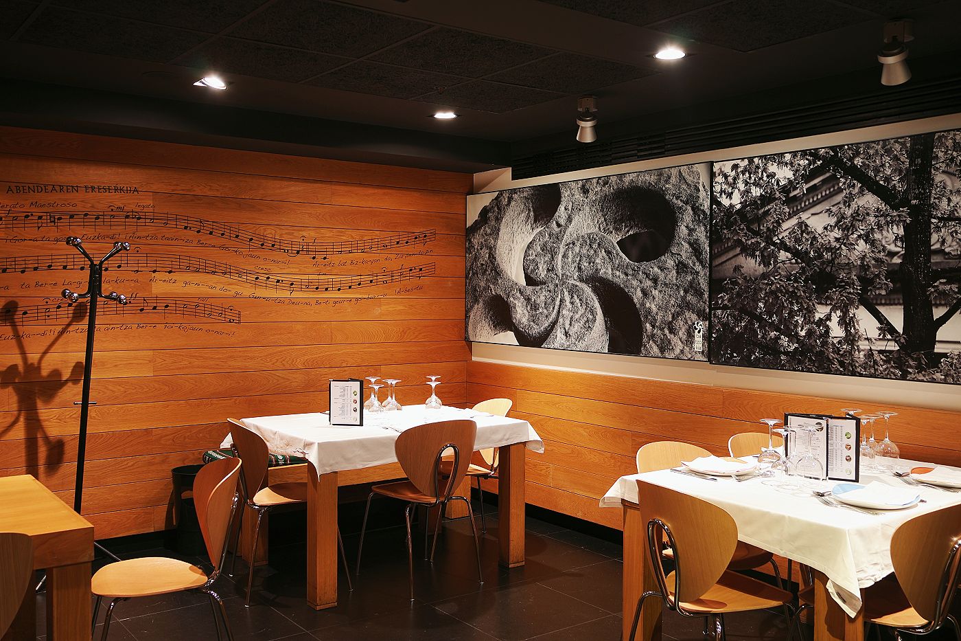 The dining room at Aralar with the tables laid, a wooden wall and large black-and-white photographs